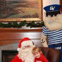 A daughter of an alum sitting with Santa & Louie.